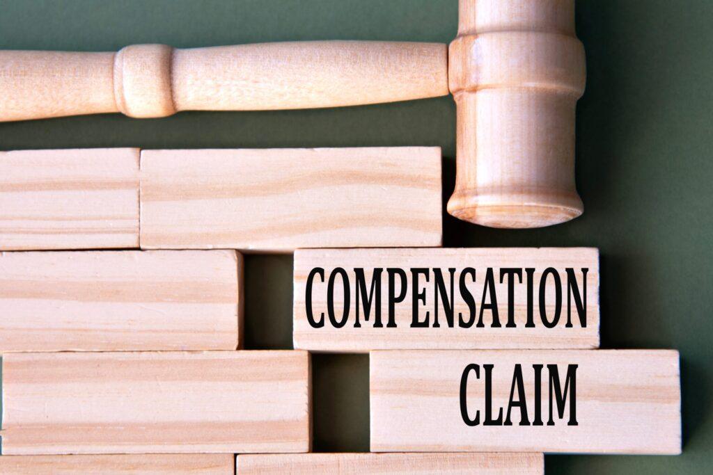 Wooden judge gavel above blocks labeled &lsquo;compensation claim,&rsquo; representing personal injury or legal damages case.