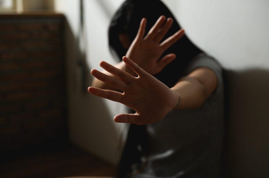 Woman holding up her hands to block the camera, symbolizing domestic violence or personal safety concerns.