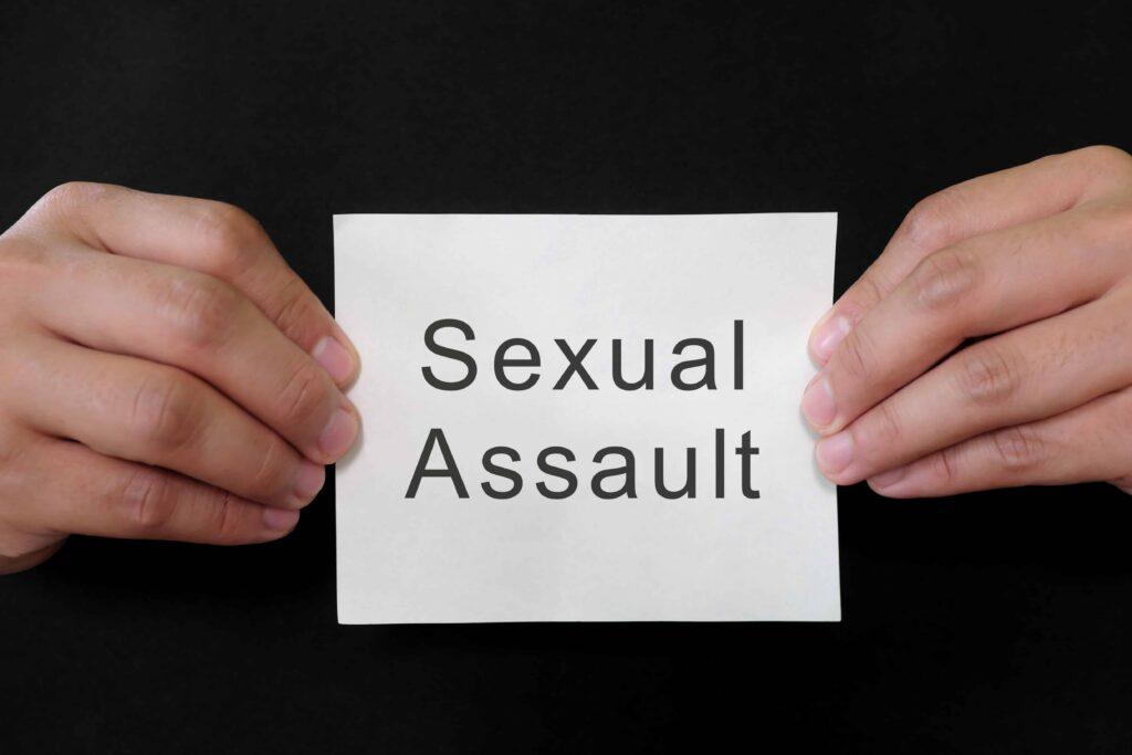 Hands holding a card with the words &ldquo;Sexual Assault,&rdquo; representing awareness of sexual assault, legal rights, and support for victims seeking justice.