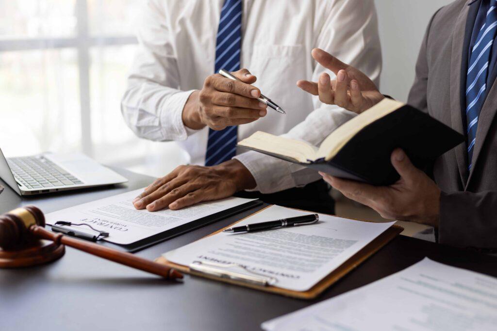 Lawyers reviewing contract documents during legal consultation with gavel and paperwork on desk.