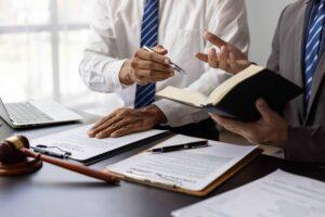 Lawyers reviewing contract documents during legal consultation with gavel and paperwork on desk.