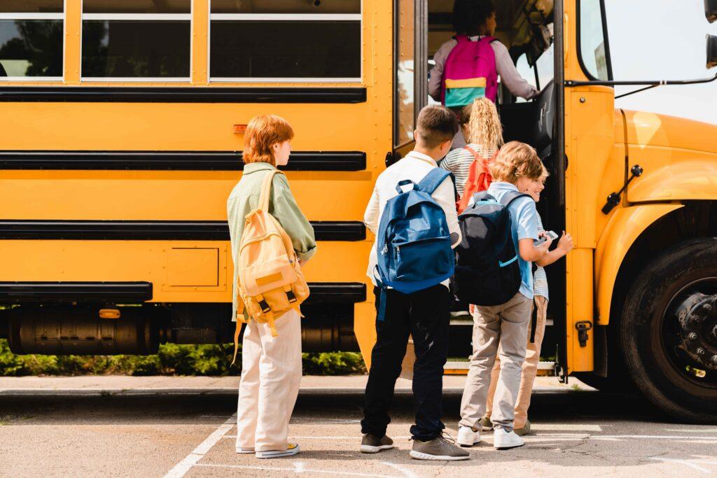 School children with backpacks boarding a yellow school bus, representing student transportation and back-to-school routine