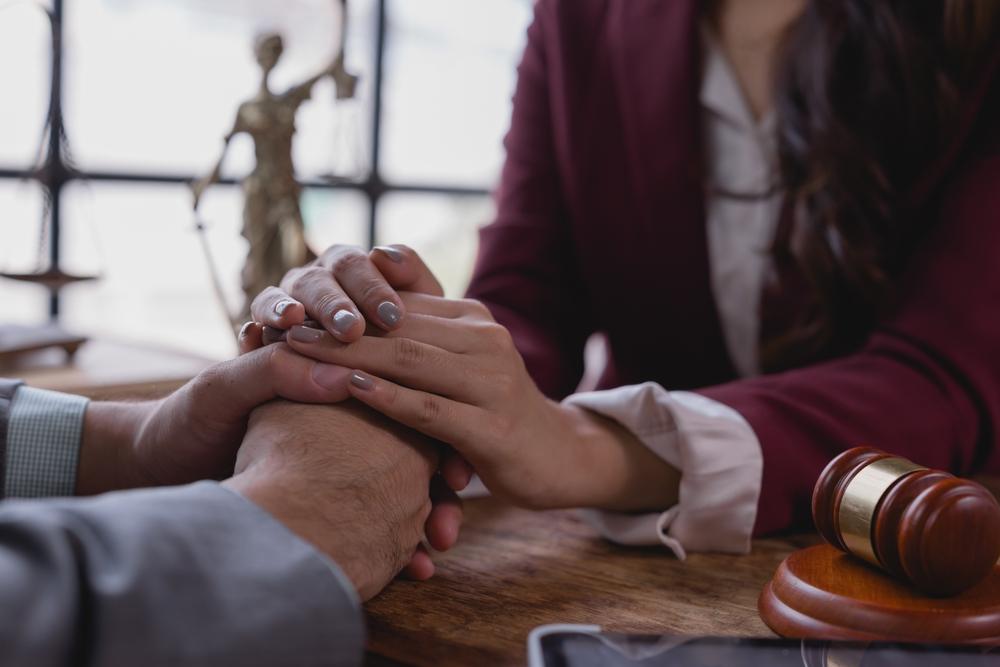 Lawyer grasping client's hands in a show of compassion