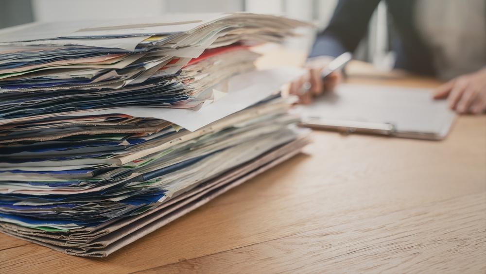 Lawyer researching case through stack of physical documents